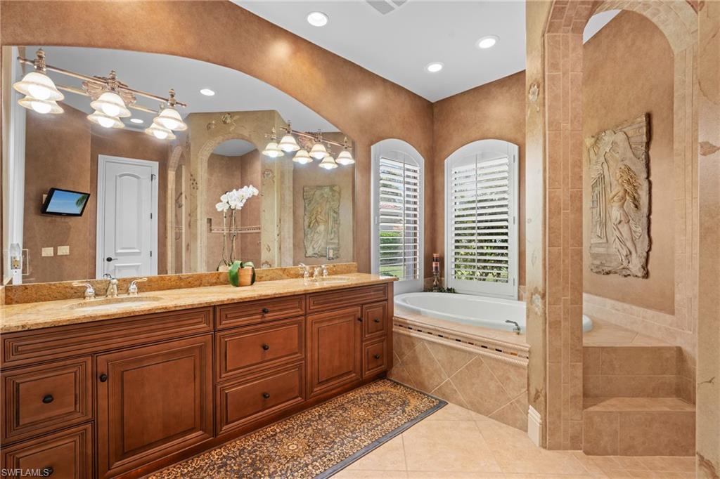 7833 Classics Drive Naples, FL 34113 - Photo 23 of 43 Bathroom with tiled tub, tile patterned floors, and vanity