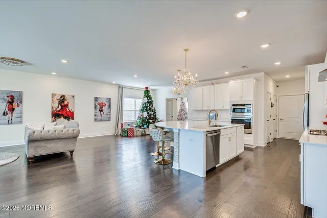 a living room with furniture and kitchen view with wooden floor