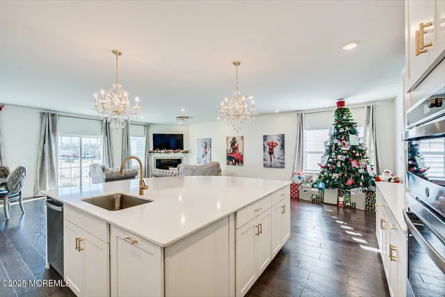 a large white kitchen with a refrigerator a stove a sink dishwasher a dining table and chairs with wooden floor