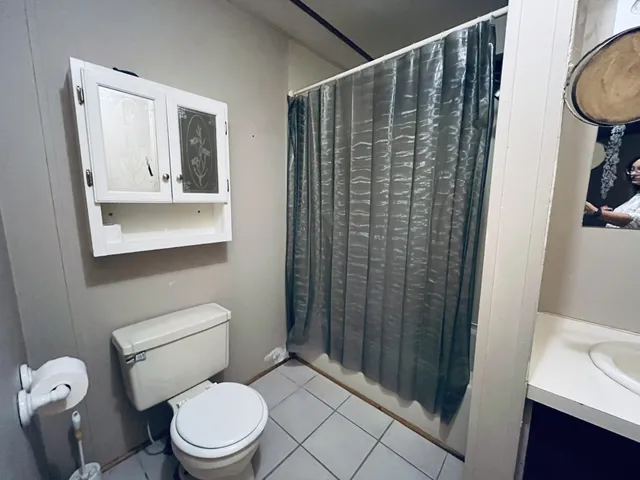 a bathroom with a sink a toilet a mirror and shower