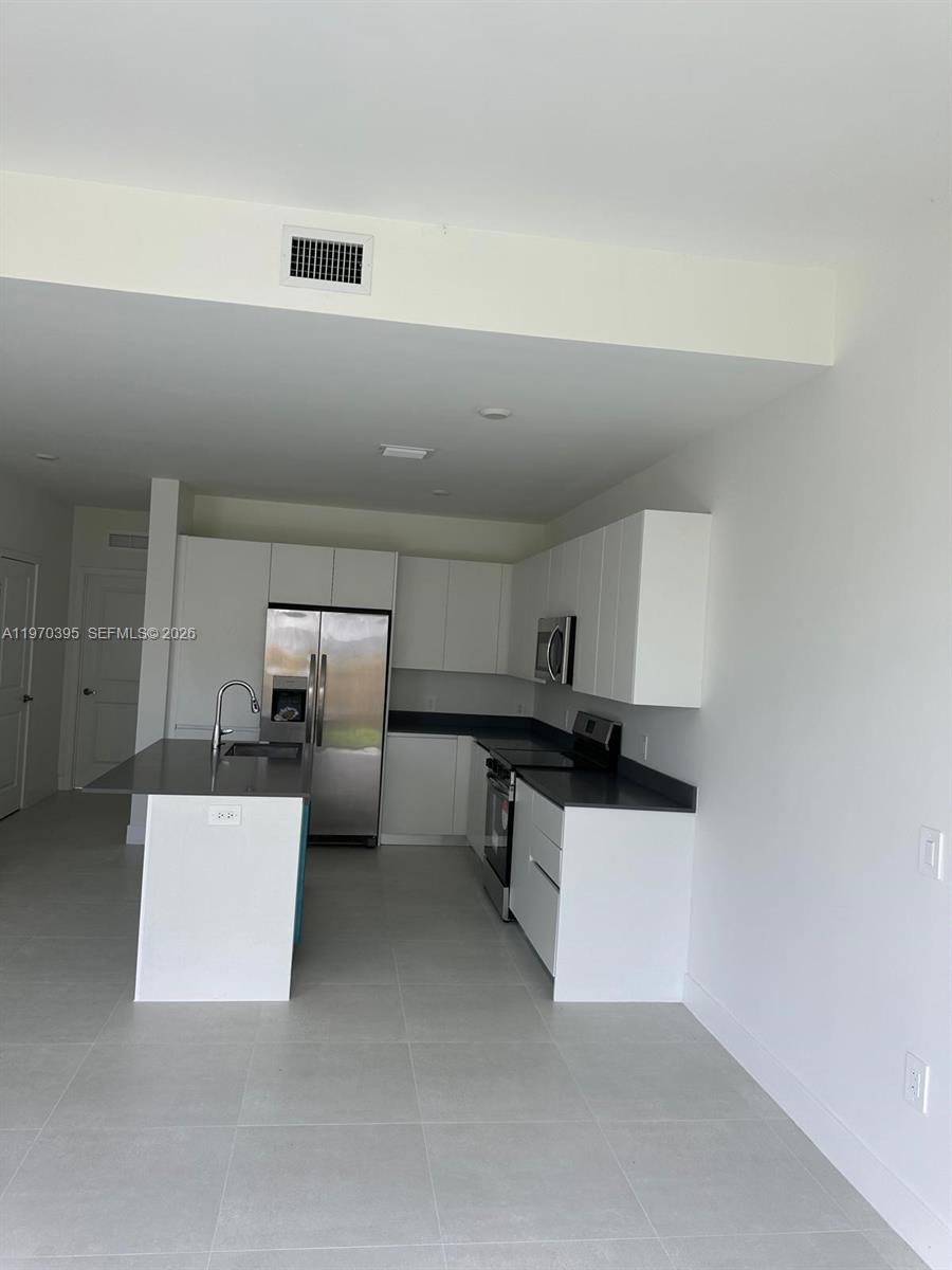 34430 Southwest 190th Avenue Homestead, FL 33034 - Photo 7 of 18 a kitchen with white cabinets and stainless steel appliances