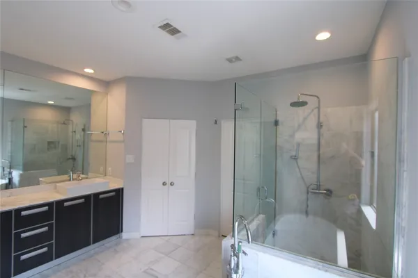 a bathroom with a tub shower sink vanity granite and a shower