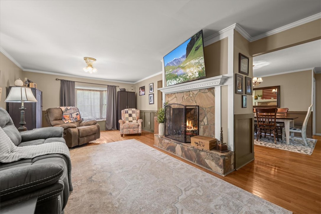 668 Marcengill Road Westminster, SC 29693 - Photo 5 of 37 A welcoming living room showcases warm wood flooring and a stone double-sided fireplace, creating a cozy atmosphere for gatherings.