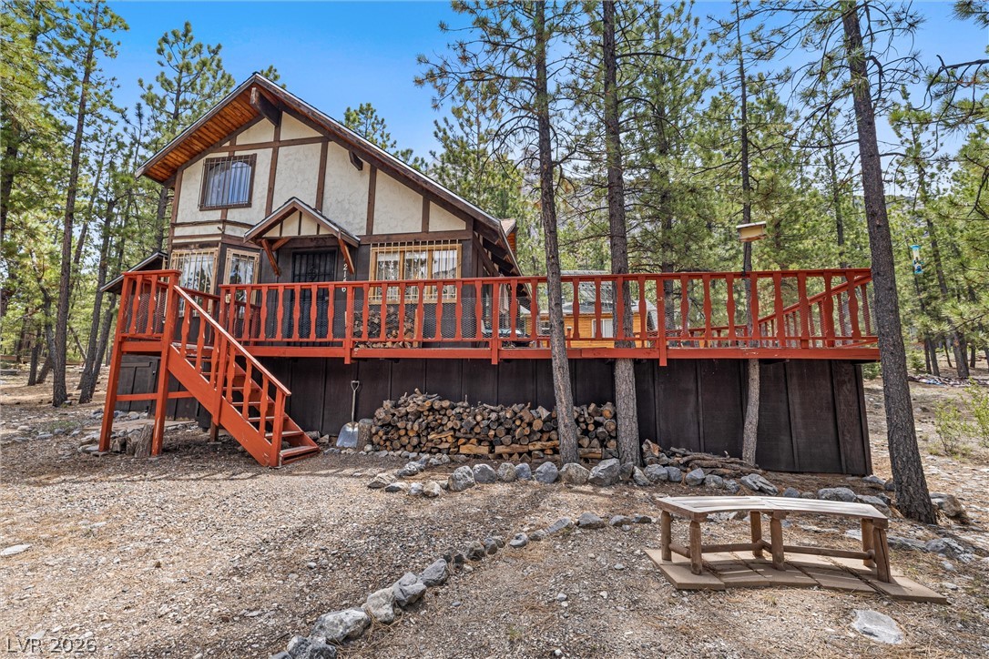 2146 Via Spes Nostra Street Mount Charleston, NV 89124 - Photo 3 of 33 A rustic cabin retreat nestled amidst a serene pine forest, featuring a spacious elevated deck for outdoor enjoyment.