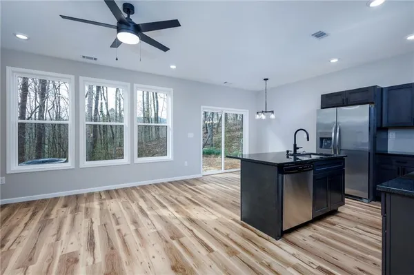 a kitchen with kitchen island granite countertop a sink appliances and cabinets
