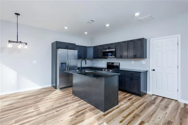 a kitchen with stainless steel appliances granite countertop a refrigerator a sink dishwasher a stove and a oven with wooden floor