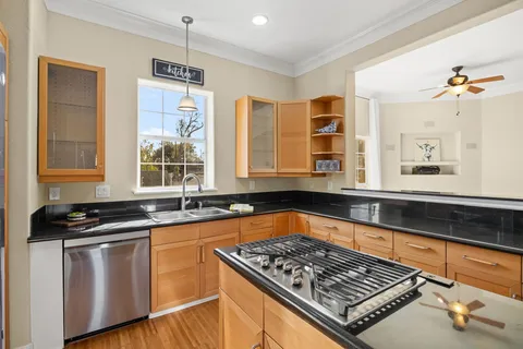 a kitchen with granite countertop a stove a sink dishwasher and a dining table with wooden floor