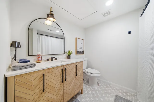 a bathroom with a granite countertop sink a toilet and a mirror