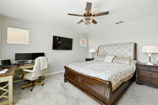 a bedroom with a bed a chair and a flat screen tv