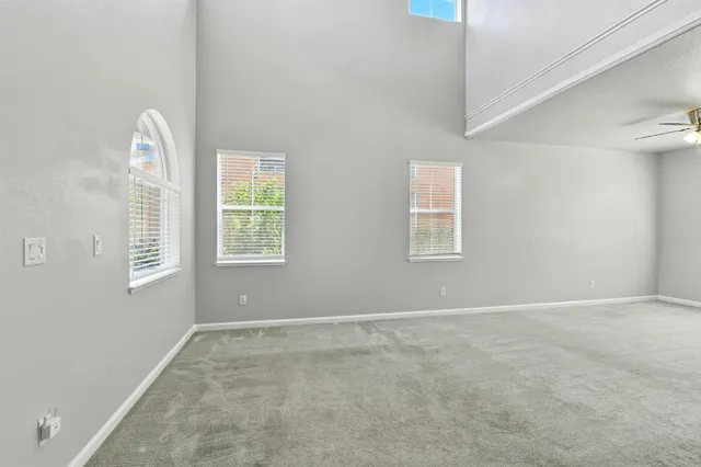 an empty room with windows and fan