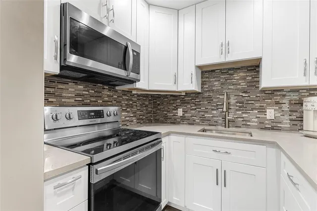 a kitchen with stainless steel appliances white cabinets and a stove top oven