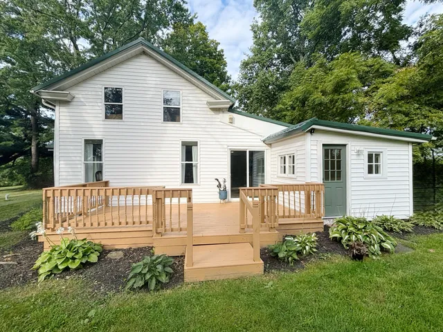 a backyard of a house with plants and large tree