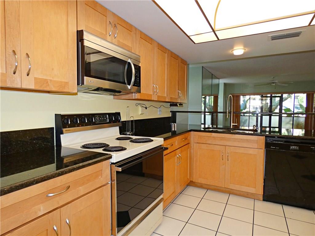 1851 Southwest Palm City Road, Unit E101 Stuart, FL 34994 - Photo 3 of 21 a kitchen with stainless steel appliances granite countertop a stove a sink and a microwave