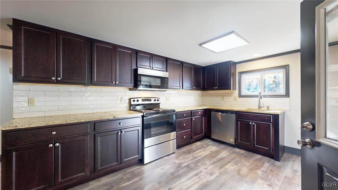 8713 Lincoln Green Drive Kunkletown, PA 18058 - Photo 4 of 42 a kitchen with stainless steel appliances granite countertop wooden cabinets a stove top oven a sink and dishwasher