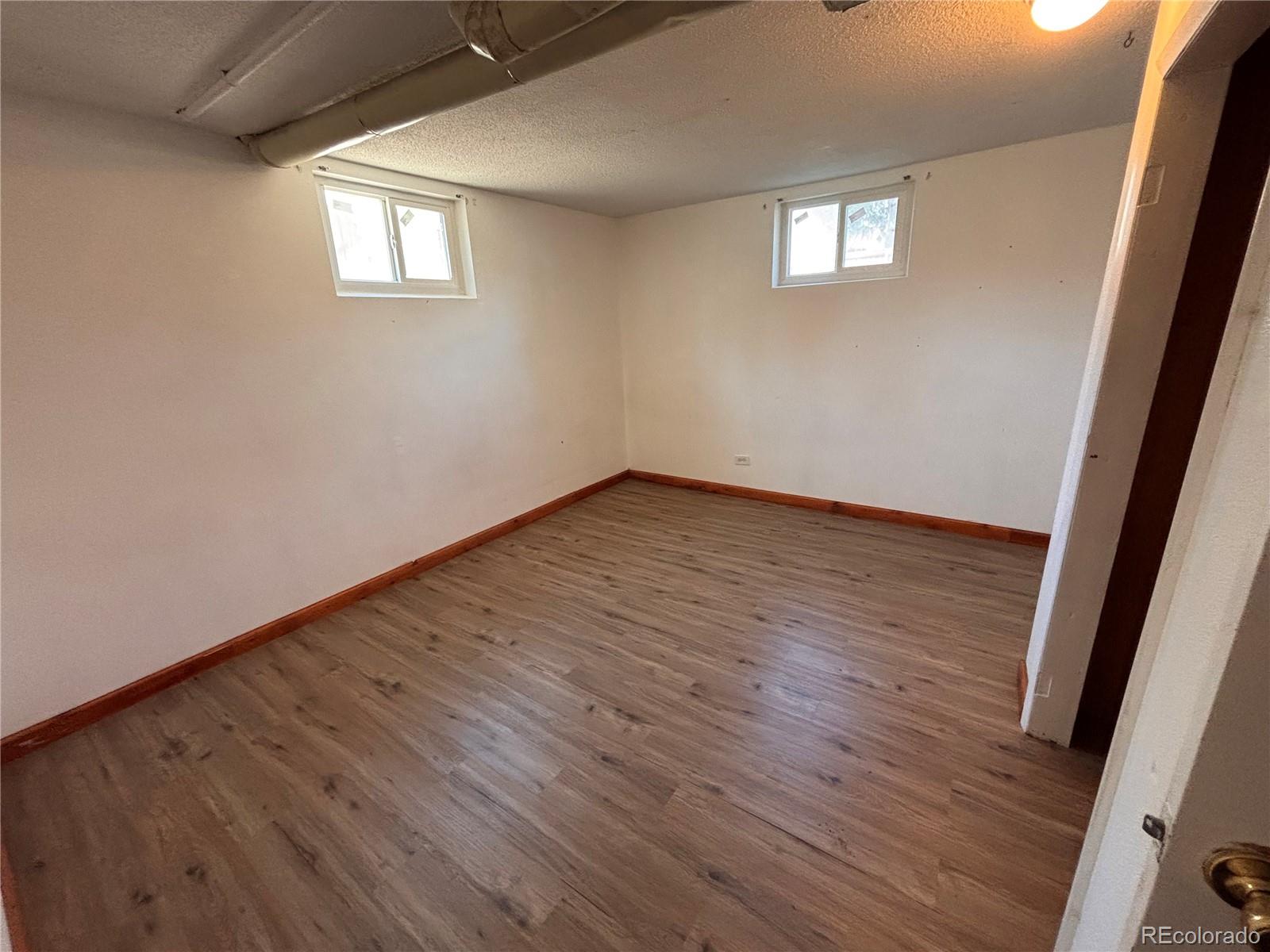2771 South Perry Street Denver, CO 80236 - Photo 28 of 40 an empty room with wooden floor and windows