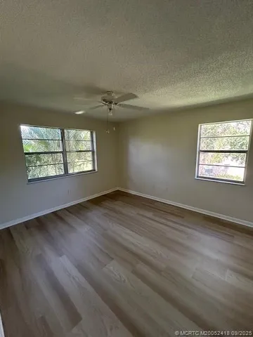 an empty room with wooden floor chandelier and windows