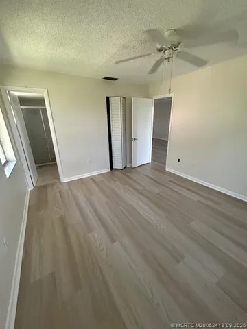 en empty room with wooden floor and ceiling fan