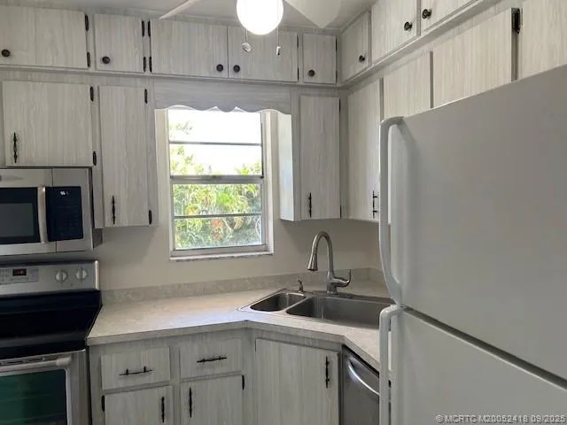a kitchen with stainless steel appliances white cabinets and a window