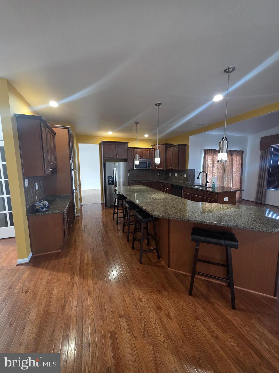 2409 Barrett Court Frederick, MD 21702 - Photo 17 of 19 a kitchen with stainless steel appliances wooden floors wooden cabinets dining table and chair