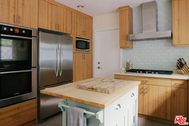 a kitchen with stainless steel appliances granite countertop a refrigerator a stove and a sink