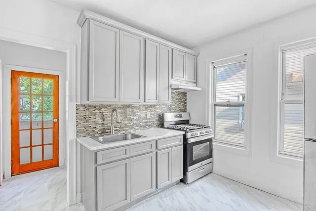a kitchen with stainless steel appliances granite countertop a stove and a white cabinets
