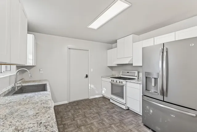a kitchen with granite countertop a refrigerator stove and sink
