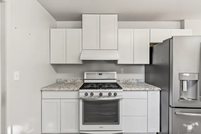 a kitchen with granite countertop white cabinets and refrigerator