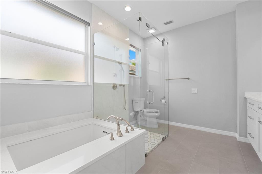 1717 Winding Oaks Way Naples, FL 34109 - Photo 18 of 29 a bathroom with a tub a sink and a large mirror