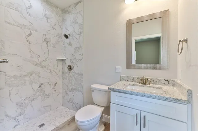 a bathroom with a granite countertop sink a toilet and a mirror