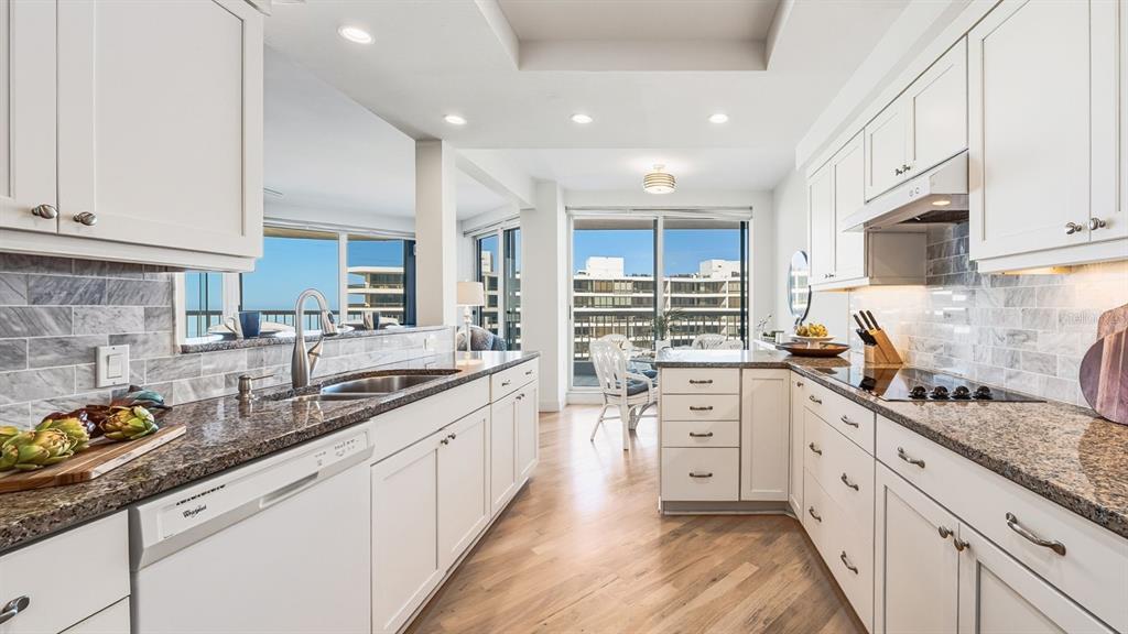 455 Longboat Club Road, Unit 707 Longboat Key, FL 34228 - Photo 27 of 69 a large kitchen with stainless steel appliances granite countertop a sink dishwasher a stove and white cabinets with wooden floor