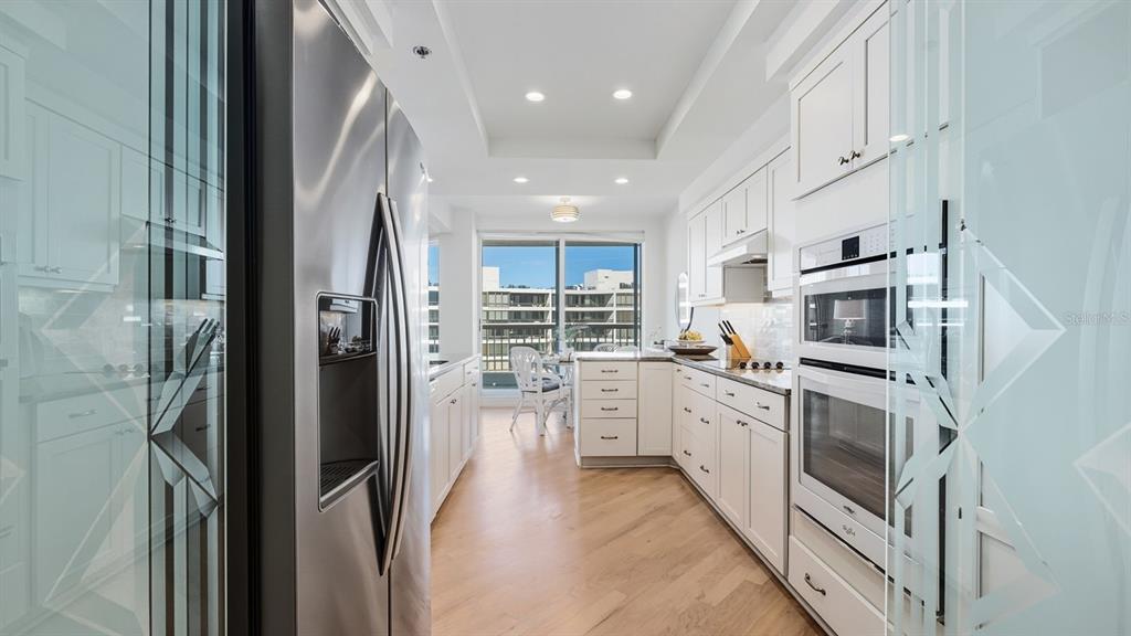 455 Longboat Club Road, Unit 707 Longboat Key, FL 34228 - Photo 28 of 69 a kitchen with white cabinets and stainless steel appliances