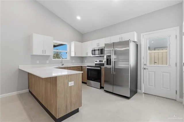 a kitchen with stainless steel appliances granite countertop a refrigerator a sink a stove and a refrigerator