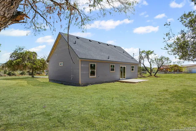 a house that is sitting in the grass with large trees