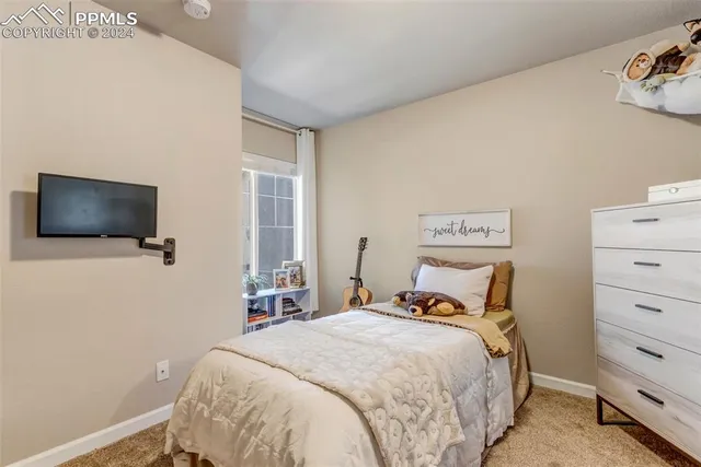 a bedroom with a bed and a flat tv screen on the dresser