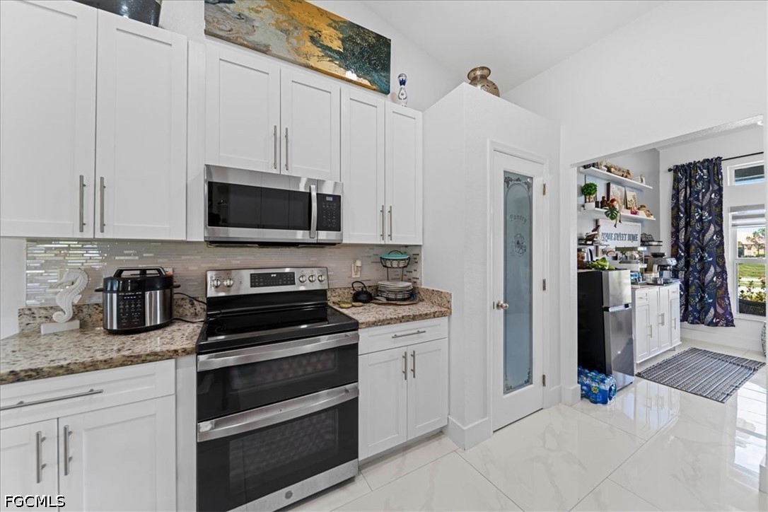 22 Nelson Road South Cape Coral, FL 33991 - Photo 18 of 43 a kitchen with granite countertop a stove and a refrigerator