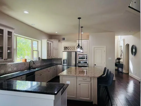 a kitchen with stainless steel appliances granite countertop a sink a stove and a wooden floors