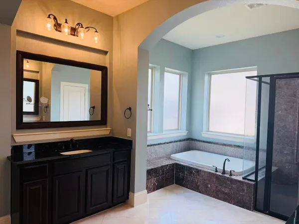 a bathroom with a tub a double vanity sink and a mirror