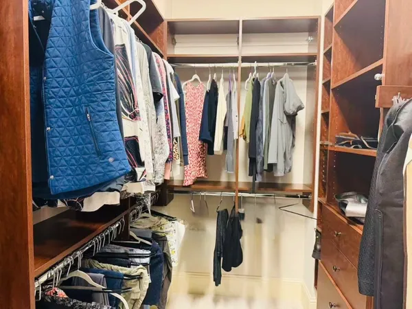 a view of walk in closet with clothes and shoes