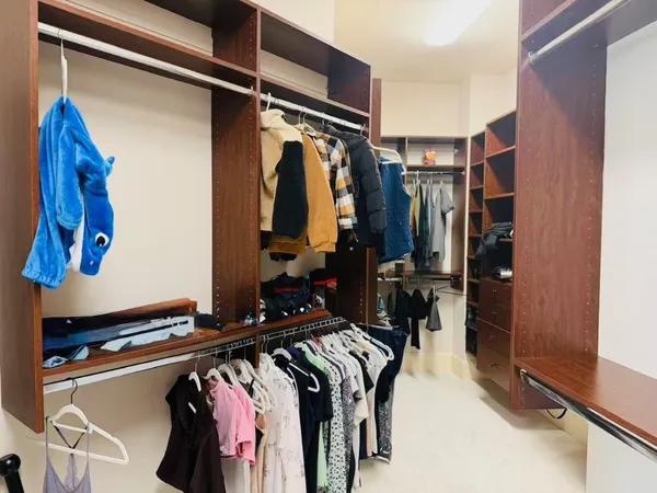 a view of walk in closet with clothes and shoes