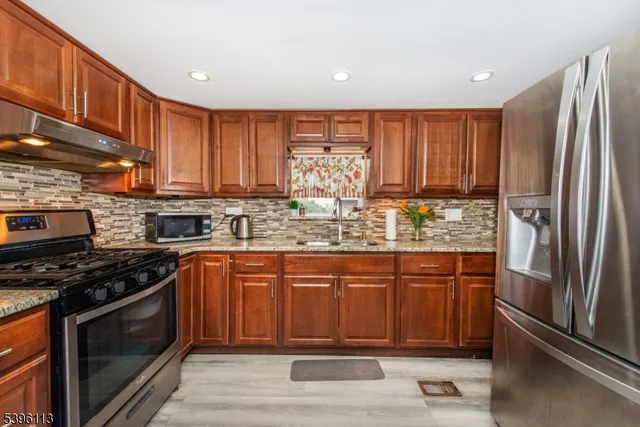 a kitchen with stainless steel appliances granite countertop a stove a sink and a refrigerator