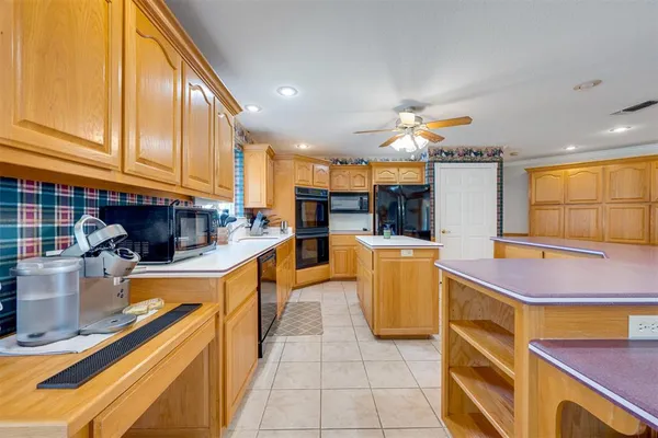 a kitchen with kitchen island granite countertop a sink a counter top space appliances and cabinets