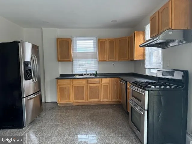 a kitchen with stainless steel appliances granite countertop a stove a sink and a microwave