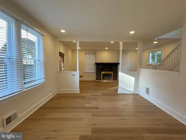 an empty room with wooden floor and a fireplace