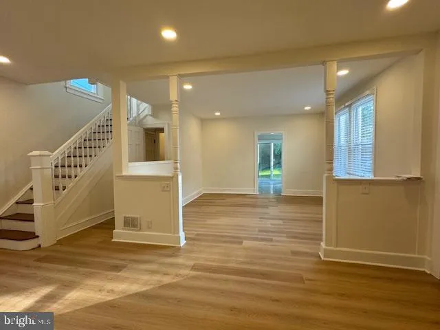 an empty room with wooden floor and windows