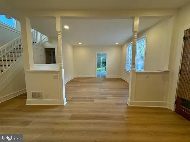 an empty room with wooden floor and windows