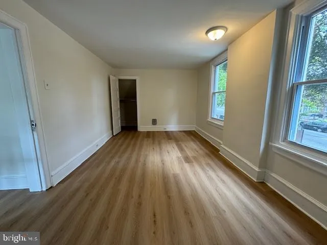 an empty room with wooden floor and windows