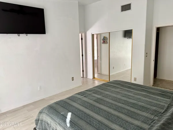 a bedroom with a bed and a flat tv screen on dresser