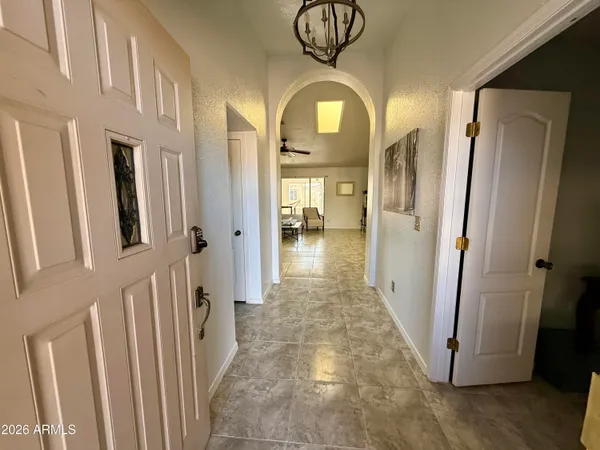 a view of a hallway with wooden floor and a chandelier