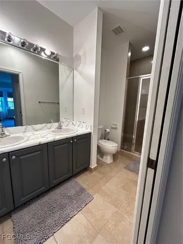 a bathroom with a double vanity sink toilet and mirror