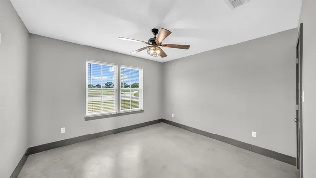an empty room with a window and a fan